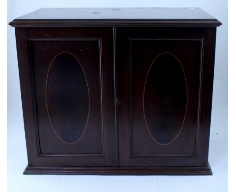 An early 20th century mahogany cross banded smoker's cabinet, the twin panelled doors reveal an interior with mixing bowl rec