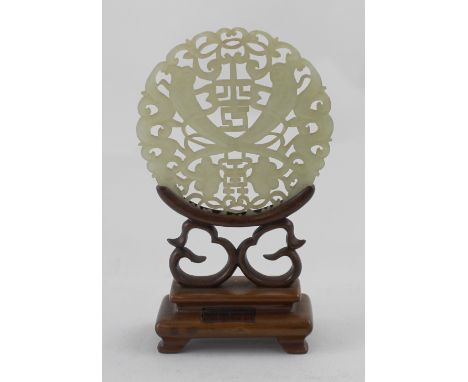 A carved jade disc on hardwood stand, height 14cm, with wax seal.