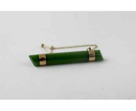 A jade bar brooch with yellow metal fittings, length 5.5cm.