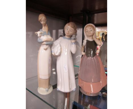 Lladro Girl Holding Lamb, 'C-28S', 26.5cm high; two Nao figurines. (3)