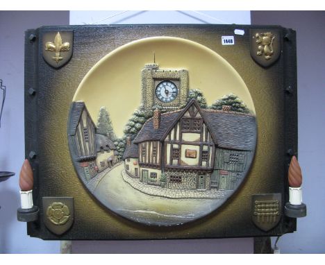 A Circa Mid XX Century Pottery Wall Plaque, featuring village scene with (later) clock to church tower, mounted in Heraldic s