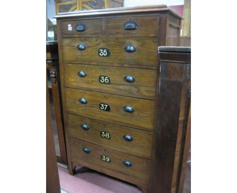 A 1930's Oak Factory/Office Chest of Two Short Drawers and Five Long Drawers, having painted metal numerals on bracket feet, 