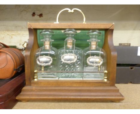 Oak and brass tantalus with 3 glass decanters and set of three hallmarked sterling silver decanter labels, Brandy, Whisky and