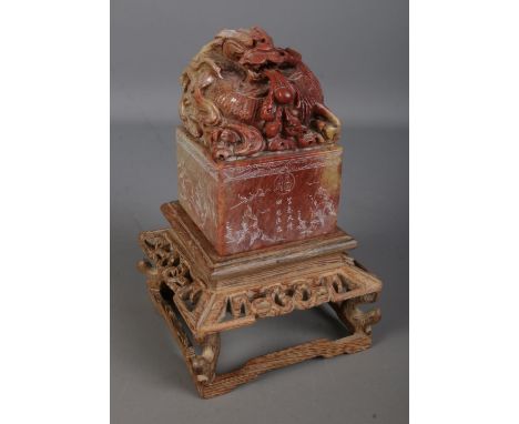 A Chinese carved soapstone seal on carved wooden stand. The seal surmounted with a Qilin with sides featuring carved calligra