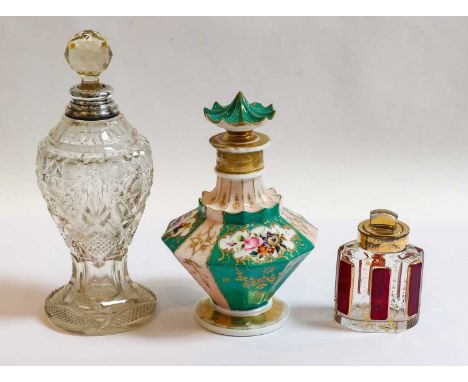 A silver-mounted cut-glass scent-bottle; a brass mounted glass scent bottle and a ceramic scent bottle, the first 21.5cm high