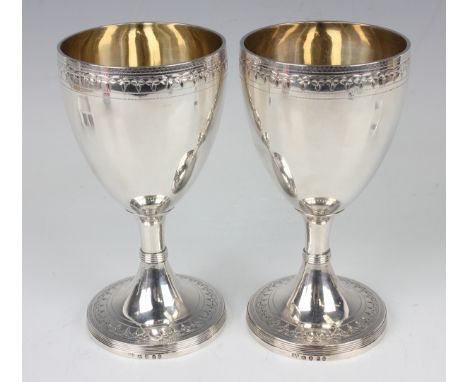 A pair of George III silver goblets, each ovoid body finely bright cut engraved with a foliate band, repeated on the circular