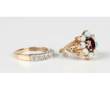 A 9ct gold, garnet and opal cluster ring, claw set with an oval cut garnet within a surround of eight circular opals, London 