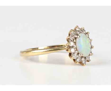 An 18ct gold ring, claw set with an oval opal within a surround of circular cut diamonds, London 1974, weight 2.8g, ring size