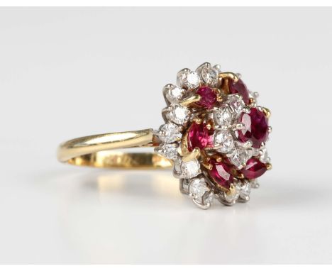 An 18ct gold, ruby and diamond cluster ring in a tiered design, mounted with the principal circular cut ruby to the centre, o