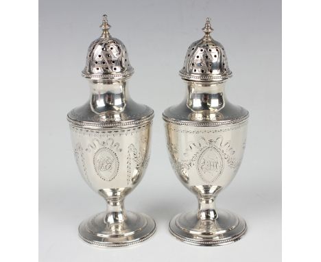 A near pair of George III silver urn shaped pepper castors with bright cut engraved decoration, each with pierced and engrave