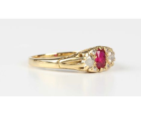 A gold, ruby and diamond ring, mounted with an oval cut ruby between two cushion cut diamonds and two small pairs of diamonds