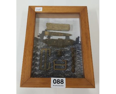 FRAMED SET DISPLAY OF WW1 RELICS TO INCLUDE BRASS FROM AN ARMY KIT, BUCKLES, STRAP PART, GRENADE PIN, 303 INERT ROUND &amp; P