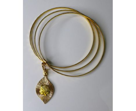 An 18ct gold triple faceted bangle, with sliding band set with a teardrop pendant depicting blind justice against a starburst