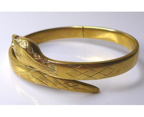 A 9ct gold snake form hinged bangle, with red stone eyes, 20.1g, 6.4cm internal width. 