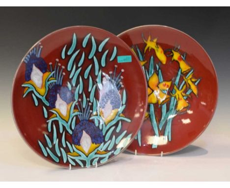 Poole Pottery - Pair of trial piece chargers by Jane Brewer 1/1 (2), both having floral decoration against a dark red ground,