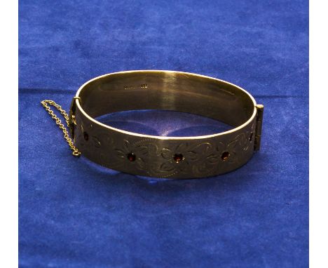 A rolled gold bangle set with garnets