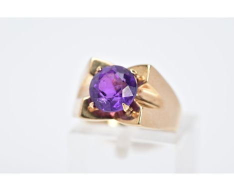 A 9CT GOLD AMETHYST RING, designed with a central claw set, circular cut amethyst within a concaved plain polished square sur