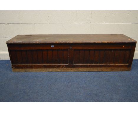 A LONG 19TH CENTURY STAINED PITCH PINE SCHOOL TUCK/STORAGE BOX/BENCH, with double panelled plank front, with a brown leathere