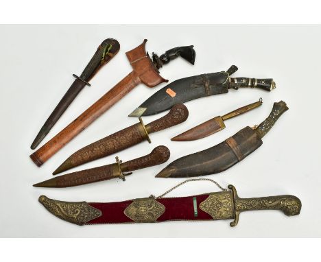 A COLLECTION OF DECORATIVE AND SOUVENIER DAGGERS, KUKRI, ETC, and a ebony handled dagger in a wooden sheath, tip of blade bro