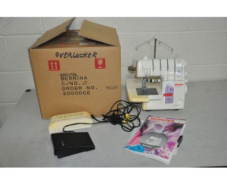 A BERNINA 2000DCE OVERLOCKING SEWING MACHINE, with treadle, manual and original box and a sewing caddy with magnifier and a c