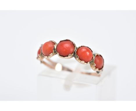 A YELLOW METAL CORAL RING, designed with five graduated coral cabochons, bifurcated textured shoulders, ring size M, approxim
