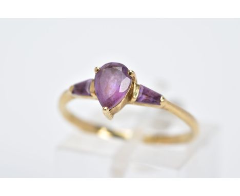 A 9CT GOLD AMETHYST RING, designed with a claw set,  pear cut amethyst, flanked by tapered cut amethyst shoulders, hallmarked