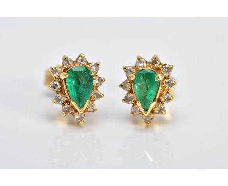 A PAIR OF YELLOW METAL, EMERALD AND DIAMOND CLUSTER EARRINGS, each designed with a central claw set, pear cut emerald, within