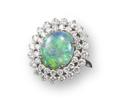 An opal and diamond cluster ring, the solid white oval-shaped opal is set within concentric surround of graduated circular-cu