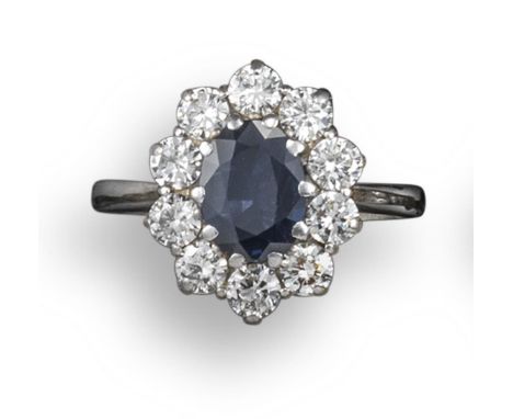 A sapphire and diamond cluster ring, the oval-shaped sapphire is set within a surround of circular-cut diamonds in white gold