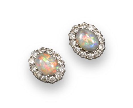 A pair of opal and diamond cluster earrings, the oval solid white opal cabochons are claw-set within a border of circular-cut