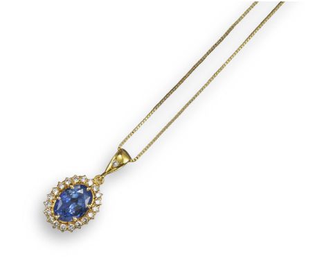 A sapphire and diamond pendant, the oval-shaped blue sapphire is set within a surround of circular-cut diamonds in yellow gol