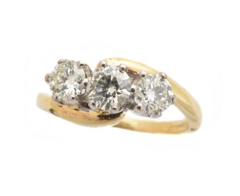 An 18ct gold diamond three stone ring,  the transition cut diamond with brilliant cut diamond sides, within a crossover setti