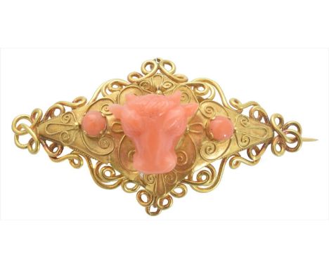 A coral brooch, designed as a carved coral bulls head with circular coral cabochon sides within a wirework surround, length 5