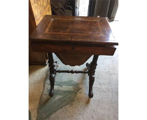 An attractive walnut work table with inlay on ornately carved and ebonised legs ending in pad feet and ceramic castors.