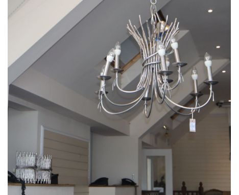 A modern silvered metal nine-light chandelier in the form of a tied bundle of twigs and six wall lights to match