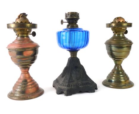 Three oil lamps, comprising Victorian cast iron oil lamp with blue glass reservoir, 30cm high, and a pair of brass effect exa