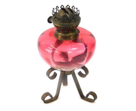 A 19thC cranberry glass oil lamp, on a brass shaped tripod base, 27cm high.