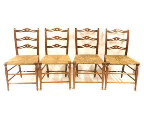 A set of four Arts and Crafts oak and rush seated dining chairs, each with a four pierced ladder back, 90cm high, 35cm wide, 