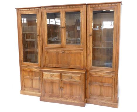 An Ercol light oak breakfront display cabinet, formed as three sections with two pillar cabinets with display case top with f