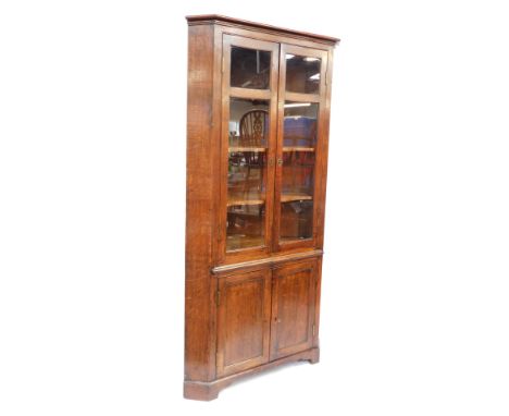 A 19thC oak standing corner cabinet, with a display cabinet top, with three shelves and two cupboard doors to the base on bra