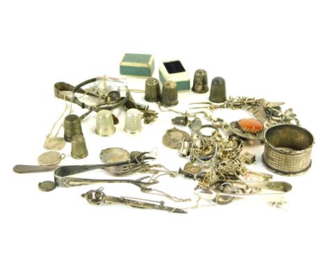 A group of silver and other trinkets and jewellery, comprising a pair of silver sugar tongs, cake fork, caddy spoon, thimbles