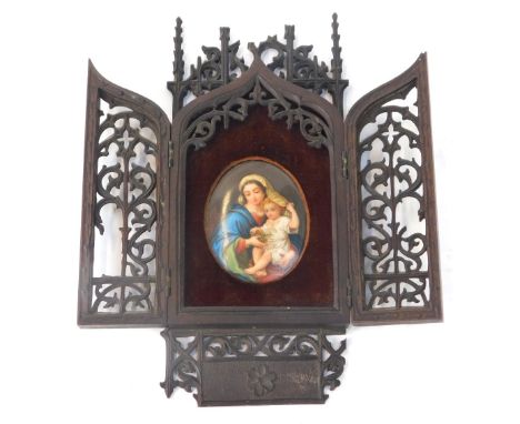 A late 19thC cased religious icon, the carved and pierced mahogany fret work case opening to reveal an oval painted porcelain