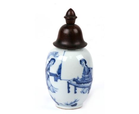A Chinese blue and white tea caddy jar with turned wooden lid. The body is decorated with figures of ladies in artistic pursu