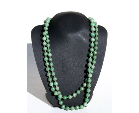 A long graduated figured jade bead necklace, 137cms (54ins) total length.