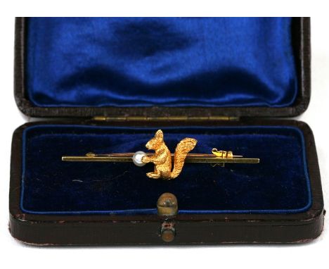 An early 20th century 18ct gold bar brooch modelled as a red squirrel holding a pearl, 4.1g, 4.5cms (1.75ins) wide.