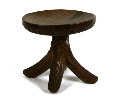 Tribal Art.  A Nigerian stool carved from a single piece with four splayed legs and all over geometric carving, 32cm (12.5 in