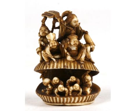 A large 19th century ivory netsuke of an open clam shell containing children, with five immortals sat on top, 6.5cm ( 2.5 ins