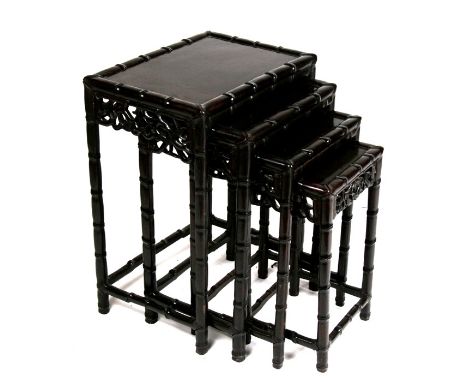 A nest of four Chinese hardwood tables with carved and pierced freeze, and simulated bamboo carving to the edges and legs. La