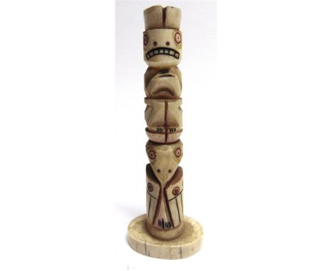 A HAIDA CARVED MARINE IVORY TOTEM POLE  with stained red and black incised detail, 13.5cm high.