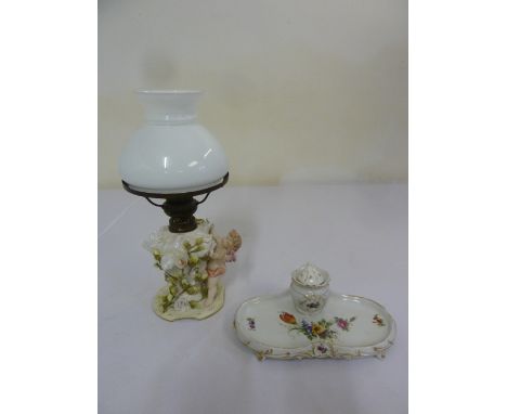 Dresden ladies inkwell and a Sitzendorf 19th century porcelain oil lamp supported by putti amidst floral decoration